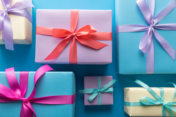 flat lay with colorful gift boxes with ribbons on blue background - Фото, изображение