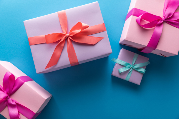 top view of colorful gift boxes with ribbons on blue background - Фото, изображение