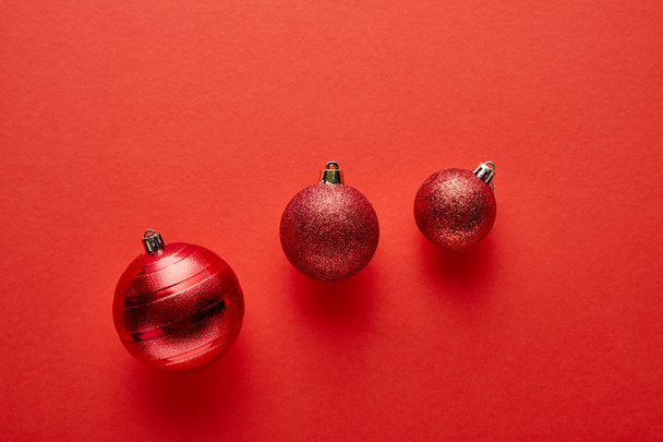 top view of shiny Christmas baubles on red background - Foto, Bild