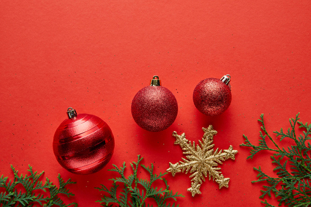 vista superior de brillantes adornos de Navidad, ramas de abeto y copo de nieve dorado sobre fondo rojo
 - Foto, Imagen