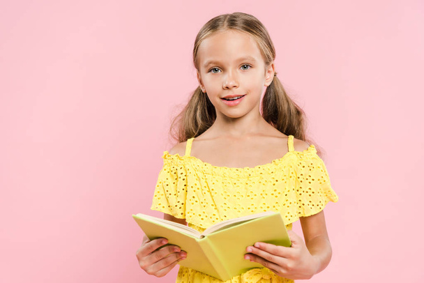enfant souriant tenant livre et regardant la caméra isolée sur rose
 - Photo, image