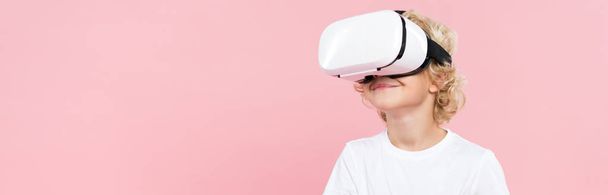 panoramic shot of smiling kid with virtual reality headset isolated on pink - Foto, Imagem