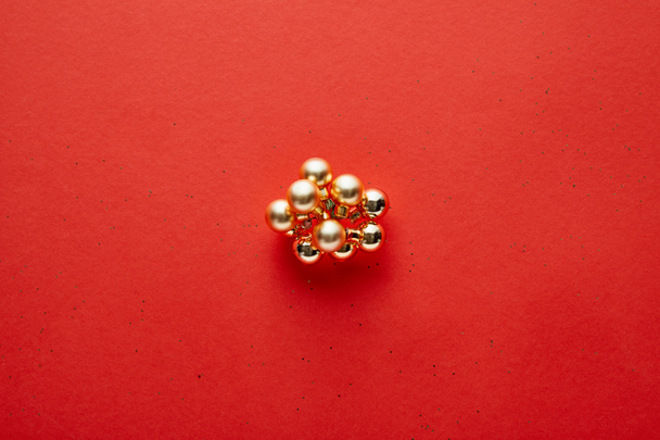 top view of shiny golden Christmas decoration on red background with copy space - Photo, Image