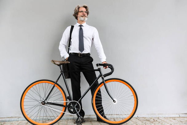 Photo of modern elderly businessman standing with bicycle - Fotoğraf, Görsel