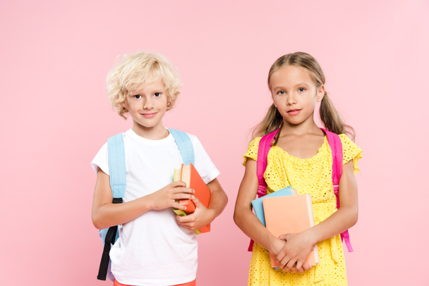 smiling schoolchildren with backpacks holding books isolated on pink - Photo, Image