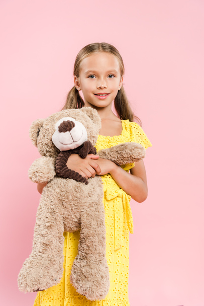 smiling and cute kids holding teddy bear isolated on pink - Foto, afbeelding