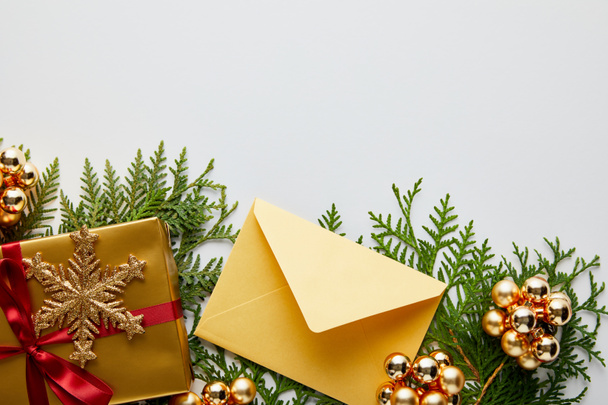 felső nézet fényes arany karácsonyi dekoráció, ajándék és boríték zöld thuja ágak elszigetelt fehér - Fotó, kép