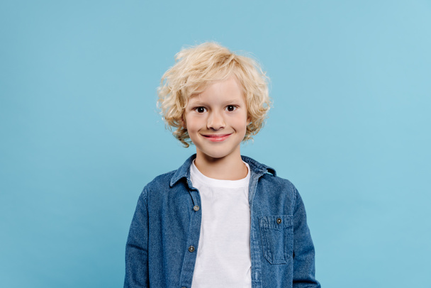 χαμογελαστό και χαριτωμένο παιδί κοιτάζοντας κάμερα απομονωμένη σε μπλε  - Φωτογραφία, εικόνα
