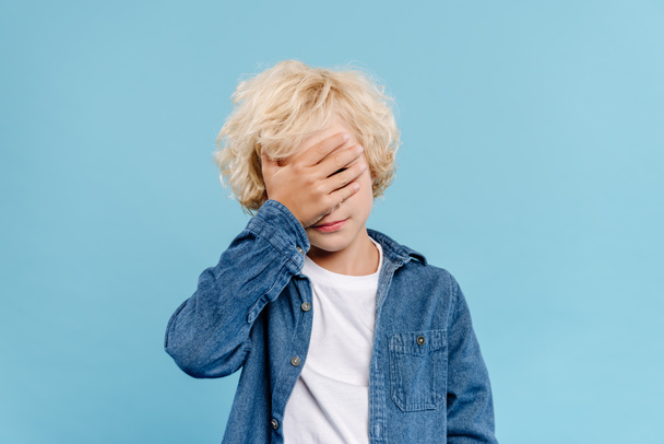 tired and cute kid obscuring face isolated on blue  - Foto, Bild