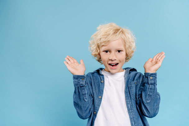smiling and shocked kid with outstretched hands looking at camera isolated on blue  - Foto, Bild