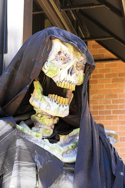Close up Grim reaper.Close-up de una sombría estatua de segador.Disfraz de Halloween fantasma esqueleto aterrador con un abrigo con capucha / Parca con cráneo en capucha negra en la oscuridad
. - Foto, Imagen