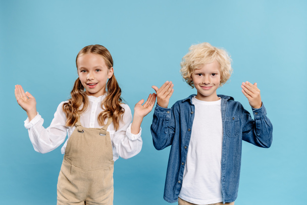 smiling and cute kids with outstretched hands looking at camera isolated on blue  - Photo, image