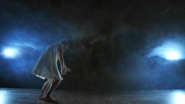 Una giovane ballerina a piedi nudi salta sul palco e si muove al rallentatore in un abito bianco allentato
 - Filmati, video