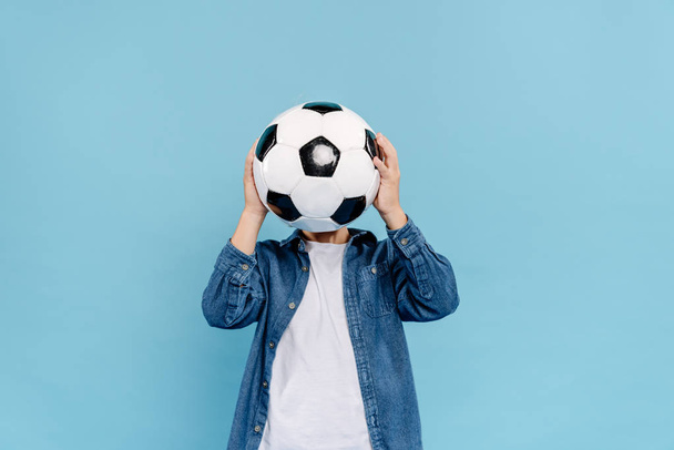 kid obscuring face with football isolated on blue  - Фото, зображення