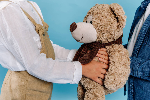 cropped view of kids holding teddy bear isolated on blue  - Фото, изображение
