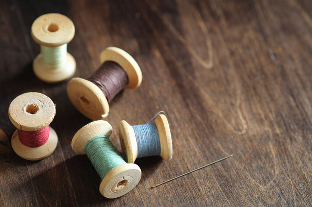 Sewing thread on a wooden background. Set of threads on bobbins  - Zdjęcie, obraz