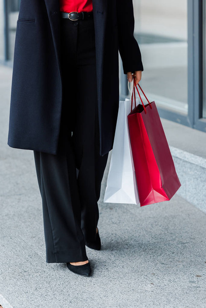 vista cortada de empresária andando e segurando sacos de compras
  - Foto, Imagem
