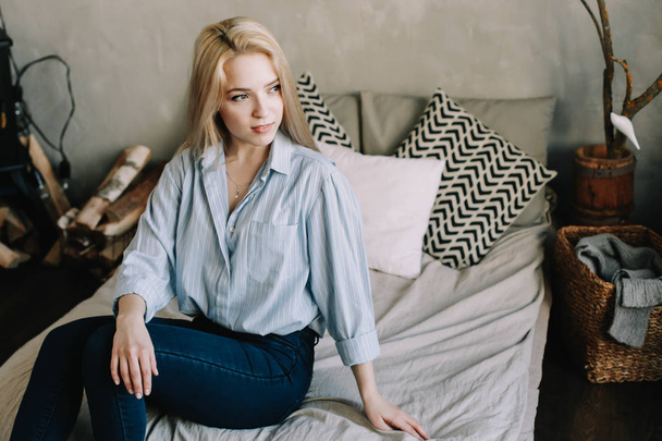 Portrait of a young beautiful woman in bed in the morning at home. Blonde girl in scandinavian interior. Good morning. Lifestyle. - Photo, image