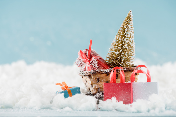 cajas de regalo y árbol de Navidad en trineo de mimbre, bolsas de compras en la nieve
  - Foto, imagen