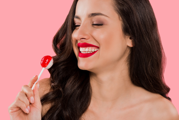 cheerful girl looking at sweet lollipop isolated on pink  - Fotó, kép