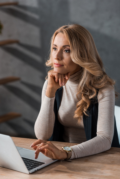 atrakcyjna i blondynka bizneswoman siedzi przy stole i odwraca wzrok  - Zdjęcie, obraz
