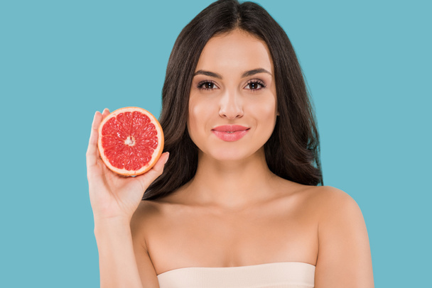 happy woman holding half of grapefruit isolated on blue  - Foto, imagen