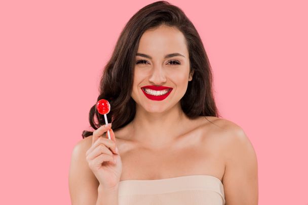 happy woman with red lips holding lollipop isolated on pink  - 写真・画像