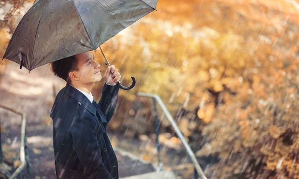 Sonbahar yağmurlu hava ve bir şemsiye ile genç bir adam - Fotoğraf, Görsel