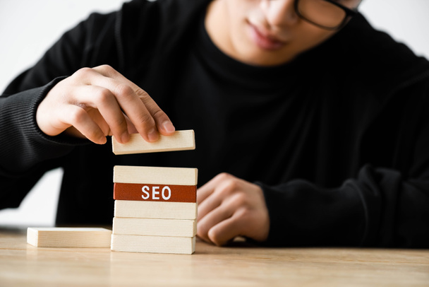 cropped view of seo manager playing with wooden rectangles with lettering seo  - Foto, afbeelding