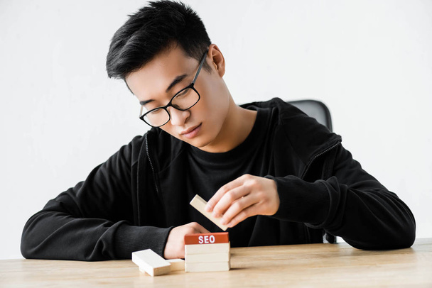 asian seo manager playing with wooden rectangles with lettering seo  - Photo, Image