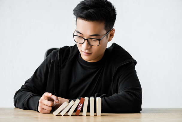 ασιατικό SEO manager παίζει με ξύλινα ορθογώνια με γράμματα SEO  - Φωτογραφία, εικόνα