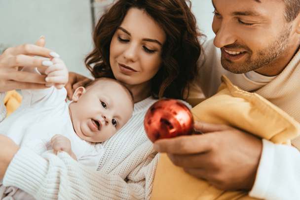 boldog apa mutatja karácsonyi labdát aranyos csecsemő fekvő anyák kezét - Fotó, kép