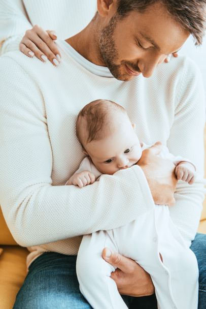 partial view of woman touching shoulders of husband holding adorable infant - Fotoğraf, Görsel