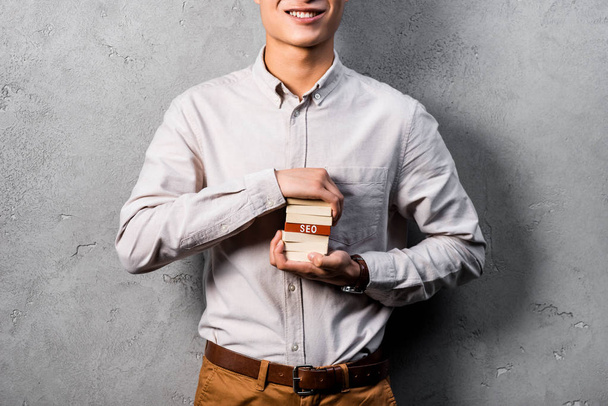 abgeschnittene Ansicht eines lächelnden SEO-Managers, der Holzrechtecke mit dem Schriftzug SEO hält  - Foto, Bild