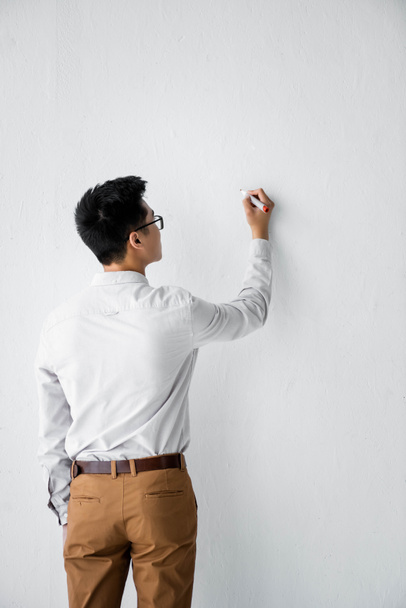 πίσω όψη του διαχειριστή SEO γράφοντας σε λευκό τοίχο  - Φωτογραφία, εικόνα