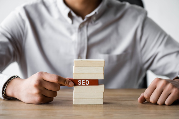 cropped view of seo manager holding wooden rectangle with lettering seo  - Photo, Image