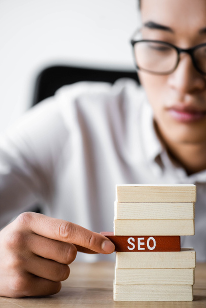 selective focus of asian seo manager holding wooden rectangle with lettering seo  - Photo, Image