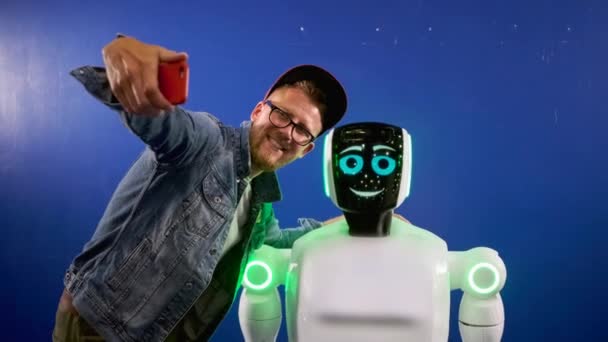 Emotional robot posing for selfie of cheerful man - Footage, Video