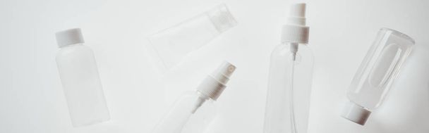 panoramisch shot van witte flessen met vloeistoffen ob witte achtergrond  - Foto, afbeelding