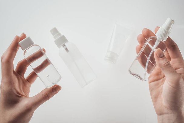 bijgesneden weergave van vrouw met flessen met vloeistoffen op witte achtergrond  - Foto, afbeelding