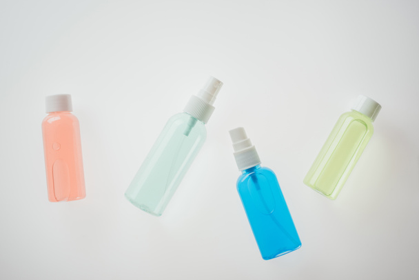 bovenaanzicht van kleurrijke flessen met vloeistoffen op witte achtergrond  - Foto, afbeelding