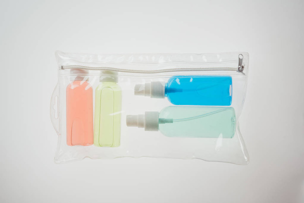 top view of colorful bottles with liquids in cosmetic bag on white background  - Fotó, kép