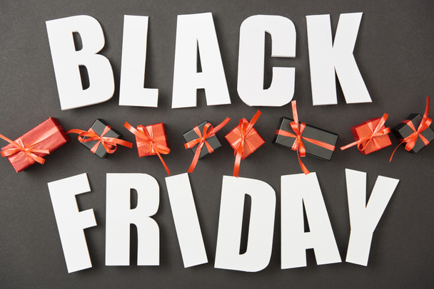 top view of black friday white lettering near presents on black background - Photo, Image