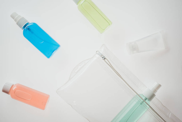Draufsicht auf Kosmetikbeutel und Flaschen mit Flüssigkeiten auf weißem Hintergrund  - Foto, Bild