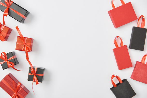 top view of black and red presents and shopping bags on white background - Foto, afbeelding