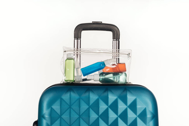 travel bag with cosmetic bag with colorful bottles with liquids isolated on white - Photo, Image