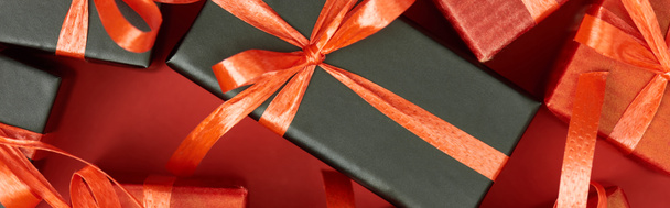 Draufsicht auf Geschenkboxen mit Schleifen und Bändern auf rotem Hintergrund, Panoramaaufnahme - Foto, Bild