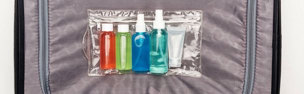photo panoramique de sac cosmétique transparent avec des bouteilles colorées sur le sac de voyage
  - Photo, image