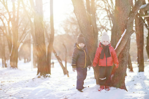 słodkie dzieci w ciepłe ubrania gry w parku zimowym  - Zdjęcie, obraz
