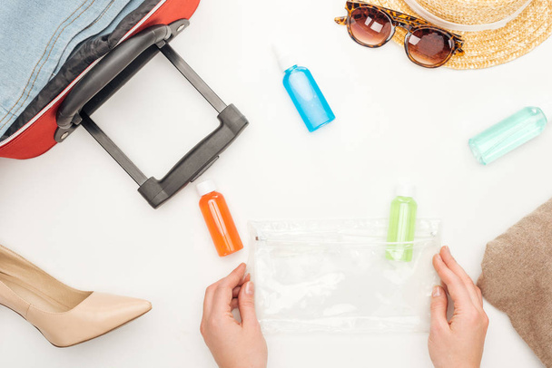 kivágott kilátás nő gazdaság kozmetikai táska színes palackok fehér alapon - Fotó, kép